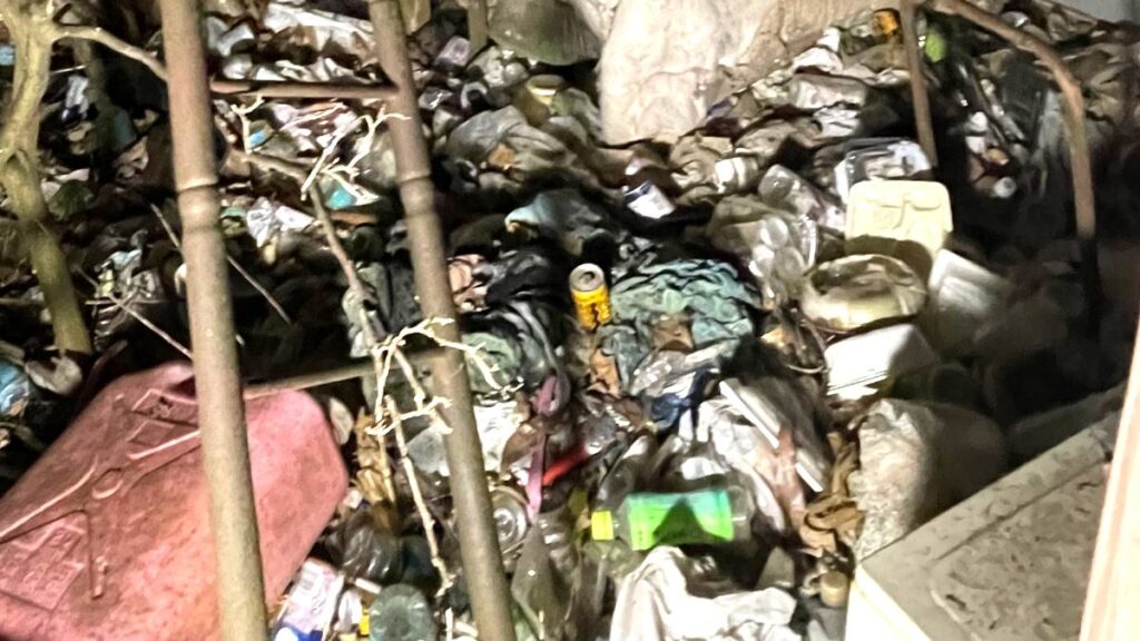 床一面に散乱した空き瓶や生活ごみ