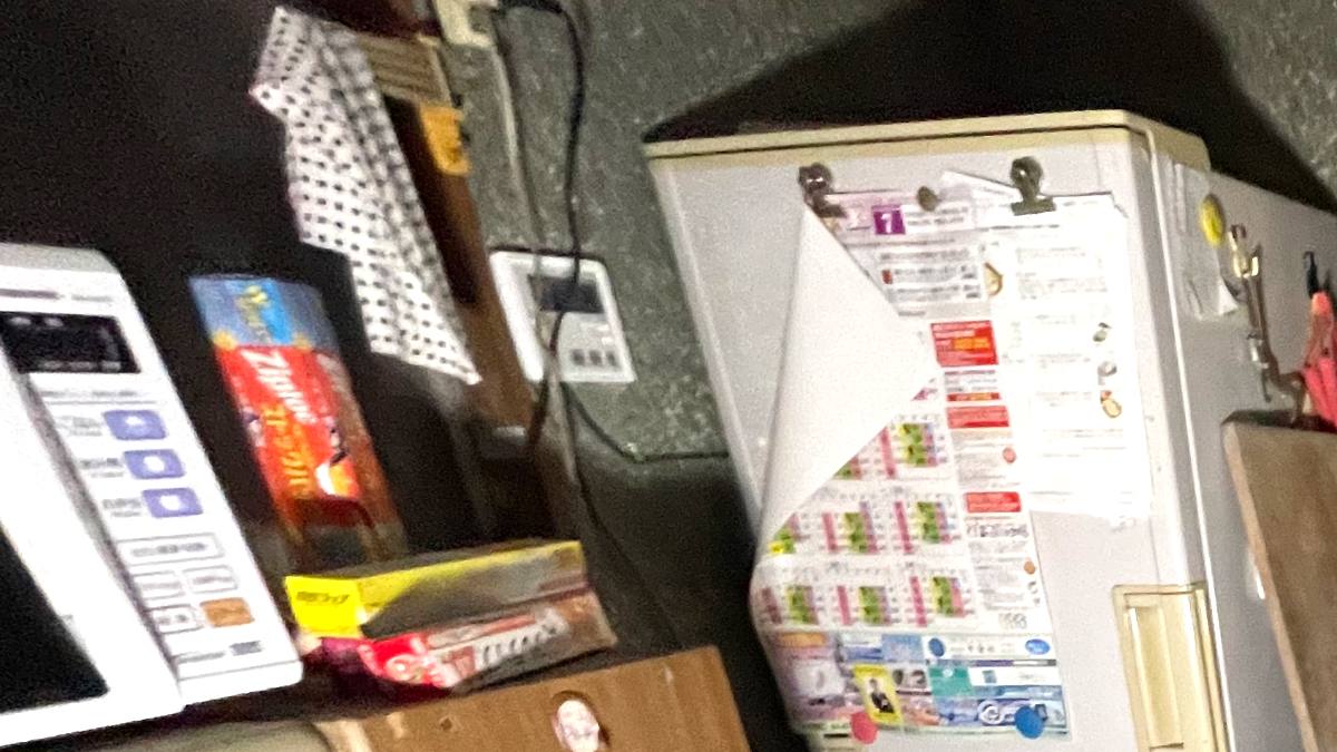 物が積み上がった台所の棚と電子レンジ