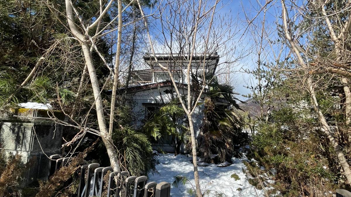 雪に埋もれた山あいの建物と門扉