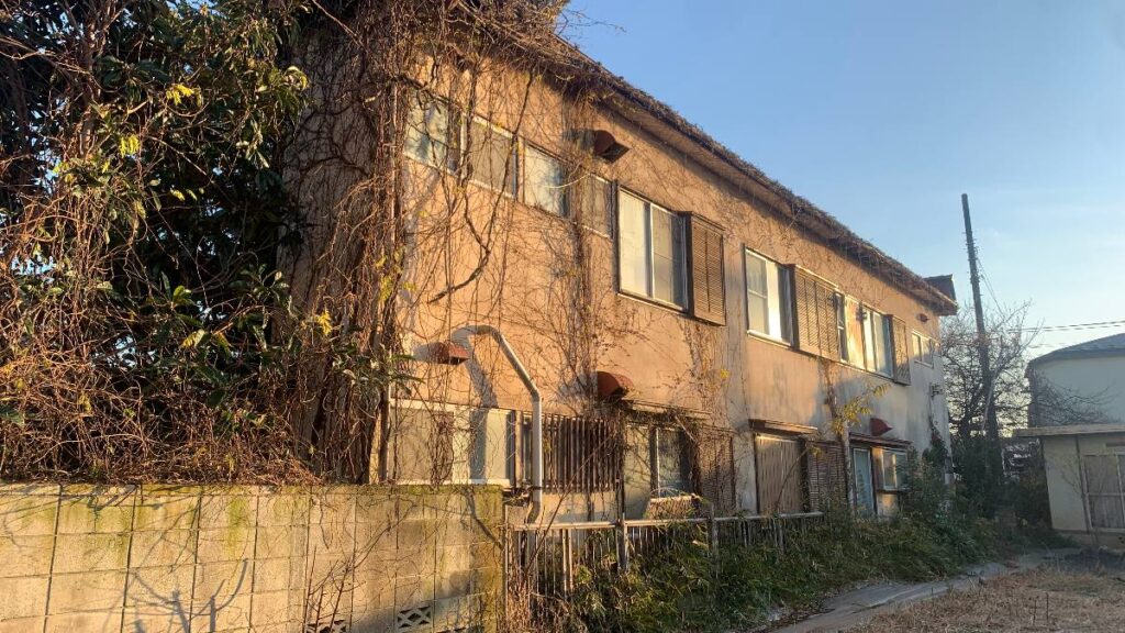 蔦に覆われた二階建ての木造アパート